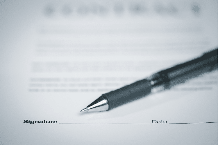 a pen laying on top of a contract near the signature line